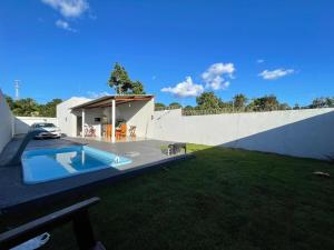 a backyard with a swimming pool and a white wall at Casa com piscina e garagem privativa in Barra do Garças