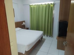 een slaapkamer met een bed en een groen gordijn bij flat 2 qtos Golden Dolphin Roberto Imoveis in Caldas Novas +16 foto's
