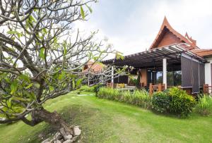 una casa con un patio verde delante de ella en Baan Souchada Resort & Spa en Sara Buri