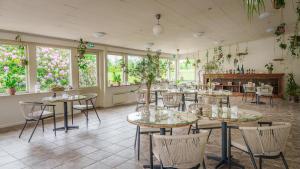 a dining room with tables and chairs and plants at Morup Mølle Kro in Bedsted Thy