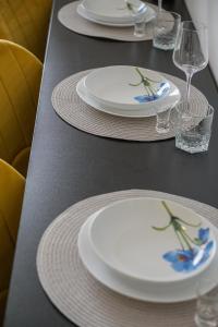three white plates on a table with wine glasses at Apartment Poprad in Poprad