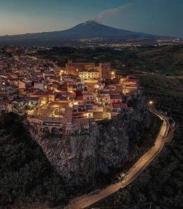 an aerial view of a town on a mountain at night at Il palazzo Dei Normanni in Motta SantʼAnastasia