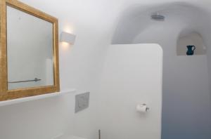 a mirror on a wall next to a bathroom at Aegea Cave Houses in Mesaria +33 photos