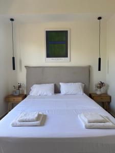 a large white bed with two towels on it at Proti Mare Villa by Toffee Homes in Marathopoli
