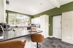 a kitchen with green walls and a counter at Central Malham Wellbeing Escape, 1-bed cottage with yoga studio & new superfast WiFi in Malham