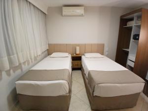 a hotel room with two beds and a desk at Landmark Residence - OFICIAL in Sao Paulo
