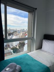 een slaapkamer met een bed en een groot raam bij Apart Metropolitan in Buenos Aires