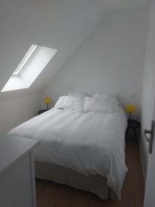 un letto bianco in una camera bianca con finestra di Maison Ile de Groix & sa voiture a Groix