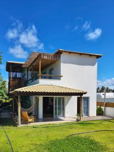 een wit huis met een balkon en een gazon bij Casa Duna - Family Friendly in São Miguel do Gostoso