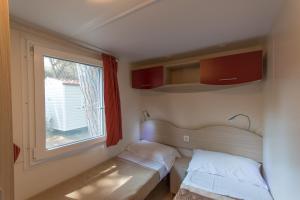 um pequeno quarto com 2 camas e uma janela em Village Camping Hawaii em Albinia
