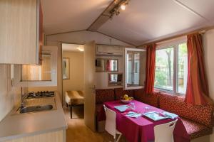 a kitchen with a table with a purple table cloth at Village Camping Hawaii in Albinia