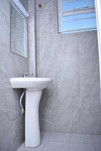 ein Badezimmer mit einem weißen Waschbecken und einem Spiegel in der Unterkunft Cozy homes in ruiru, OJ in Gatunga