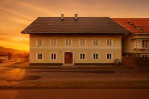 a white house with a sunset in the background at SMS-Homes I Auszeit am See #1 in Waltenhofen