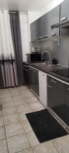 a kitchen with stainless steel appliances and a tile floor at LOCATION SAISONNIERE VILLEJUIF à 15 MIN en voiture DE PARIS in Villejuif