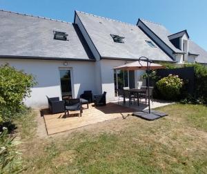 dom z drewnianym tarasem ze stołem i krzesłami w obiekcie Maison près de la plage w mieście Lancieux