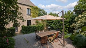 a wooden table with an umbrella in a garden at Gîte Ferme de la Chevêche & Jacuzzi Namur in Sart-Saint-Laurent
