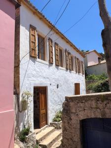 a white house with wooden windows and a gate at Akil Villa in Dhërmi