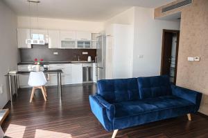 Una sala de estar con un sofá azul y una cocina. en Bright and Cozy Apartment in Vienna Gate, en Bratislava 3 fotos más
