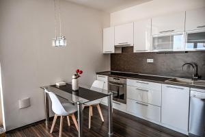 Una cocina con gabinetes blancos y una mesa y sillas. en Bright and Cozy Apartment in Vienna Gate, en Bratislava