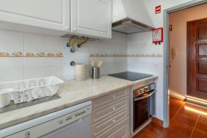 a kitchen with white cabinets and a counter top at Priolo's Nest - Azores Butler in Bicas