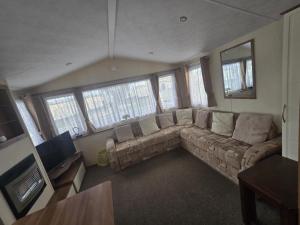 a living room with a large couch and windows at Chasing The Dream k52, Ingoldmells, FREE WIFI in Ingoldmells