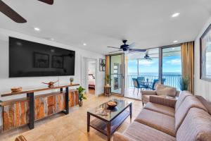 a living room with a large tv and a couch at Watch Whales and Sunsets from your Bed - Double Master Sunset Suite in Kihei