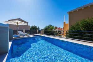 una piscina blu con ombrellone accanto a una casa di Villa "Amber" relaxation in nature with a Pool a Mlini