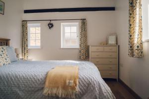 a bedroom with a bed and a dresser and two windows at Cosy Underfloor Heated 17th Century Renovated Mill with Stunning Views - Ty Felin in Beddgelert