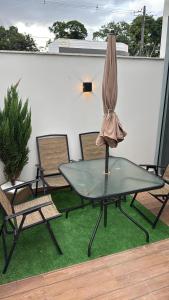 a glass table with an umbrella on top of a patio at Porto Marina Residence in Ananindeua