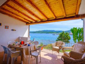 un patio con tavolo, sedie e vista sull'acqua di Sardinia Family Villas - 3 Bedrooms Apartment a Cannigione