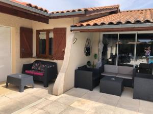 a patio with a couch and tables on a house at Villa lumineuse, logement et jardin et piscine privatifs, TV connectée in Audenge