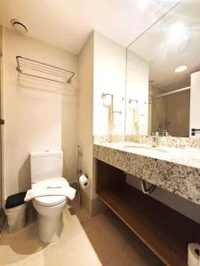 a bathroom with a toilet and a large mirror at UniHome Niterói in Niterói