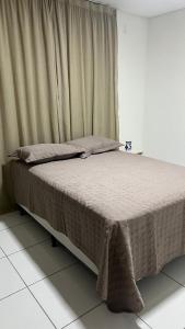 a bed in a room with a window with a bedspread at Apartamento 3 min do FIG in Garanhuns