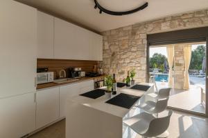 a kitchen with white cabinets and a stone wall at Olive Residence in Skala Fourkas