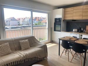 a living room with a couch and a table and a kitchen at Charmant studio d'Hardelot in Neufchâtel-Hardelot