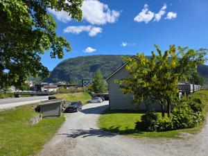 a house on the side of a road with a tree at Rom 4 i bufellesskap in Sogndal