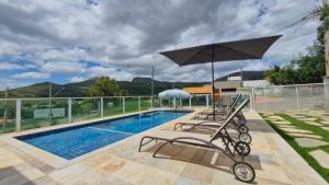 a swimming pool with two chairs and an umbrella at Casa Tô D`Boa Capitólio in Capitólio