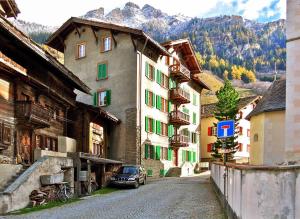 eine Straße in einer Stadt mit Gebäuden und einem Auto in der Unterkunft Grosshus Vals in Vals