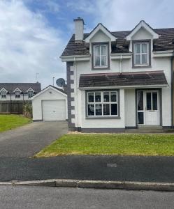 a white house with a driveway and a garage at Four Bedroom House ,Bundoran ,county Donegal in Balnacart