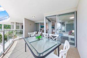 Un comedor con una mesa de cristal y sillas blancas. en Spectacular Seaviews, Pool, Modern, Free Wifi, en Airlie Beach