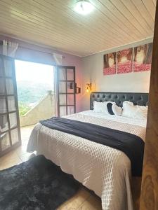 a bedroom with a large bed with a large window at Casa Sobre as Nuvens - Ideal para Casal ou Família in Campos do Jordão