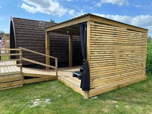 a large wooden cabin with a deck in the grass at Dolafon Luxury Glamping Pod 2 With Hot Tub in St Asaph