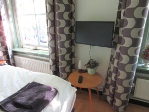 a bedroom with a bed and a table with a tv at Guesthouse Groenmarkt in Middelburg