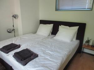 Una cama con sábanas blancas y dos toallas. en Guesthouse Groenmarkt, en Middelburg