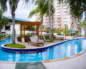 a swimming pool with chairs and a gazebo at BFC Suíte em Barra da Tijuca in Rio de Janeiro