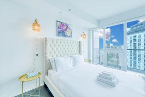 a bedroom with a white bed and a large window at RivetStays - The Jarvis in Toronto