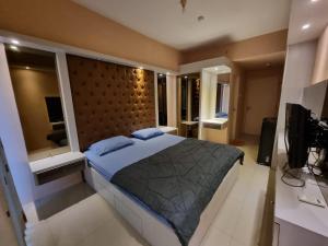 a bedroom with a large bed and a television at Pakuwon Mall Apartemen Anderson Orchard Tanglin Benson by AquHome in Surabaya