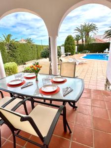 a patio with a table and chairs and a pool at CALA FORN y CLIMATIZADA in Les tres Cales