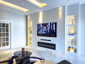 Una sala de estar con un televisor en la pared. en ELEGANT DUPLEX @ Rosedale Apartments, en Accra