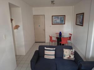 a living room with a blue couch and a table at Quarto em apartamento in Caruaru